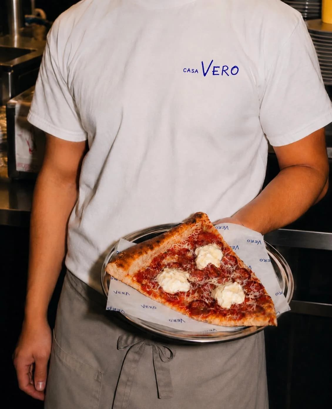 Casa Vero server holding a pizza slice on a tray